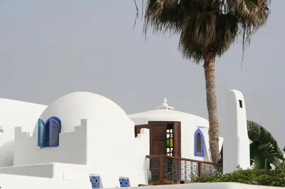 a church with a palm tree in front of it at Riad Des Plages in Bouznika