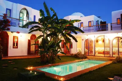 a villa with a swimming pool in front of a house at Riad Des Plages in Bouznika