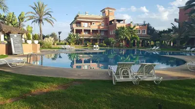 a house with two chairs in front of a swimming pool at Bouznika Charly's in Bouznika