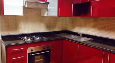 a kitchen with red cabinets and a stove and a sink at Bouznika Charly's in Bouznika