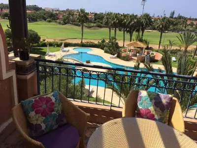 a balcony with two chairs and a view of a pool at Bouznika Charly's in Bouznika