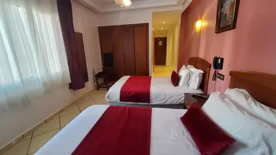 a hotel room with two beds with red and white sheets at Hôtel Amouday in Casablanca