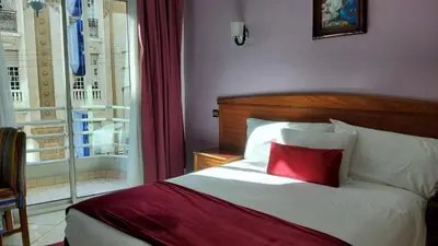 a bedroom with a bed with a red pillow at Hôtel Amouday in Casablanca
