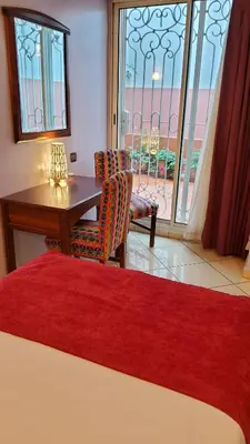 a bedroom with a desk and a table and a window at Hôtel Amouday in Casablanca