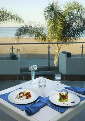 a table with two plates of food and a view of the beach at Avanti Mohammedia Hotel in Mohammedia