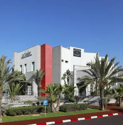 a building with palm trees in front of a street at Avanti Mohammedia Hotel in Mohammedia
