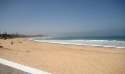 a beach with people walking on the sand and the ocean at Villa meublée face à la mer, Golf et Verdure in El Jadida