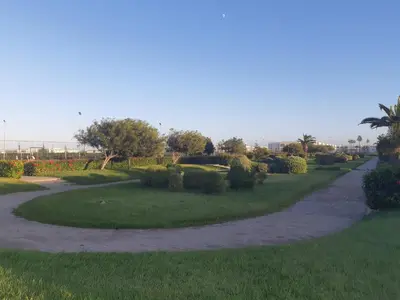 a winding path through a park with trees and bushes at Ola Blanca 1 in Dar Hamida