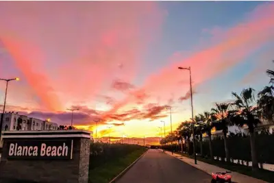 a street with a rainbow in the sky at sunset at Appartement Blanca Beach in Sidi Rahal
