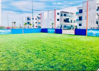 a large field of grass in front of a building at Appartement Blanca Beach in Sidi Rahal