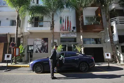 a man standing next to a blue car in the street at Park Suites Hotel Luxury Boutique Hotel in Casablanca