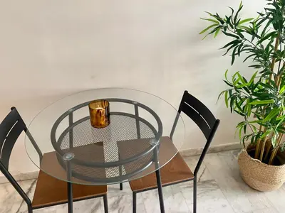 a glass table with two chairs and a plant at Appartement les pieds dans l'eau WELCOME STAY in Mohammedia