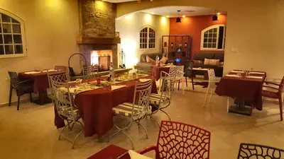 a dining room with tables and chairs and a fireplace at L'échappée belle Benslimane in O Ben Slimane