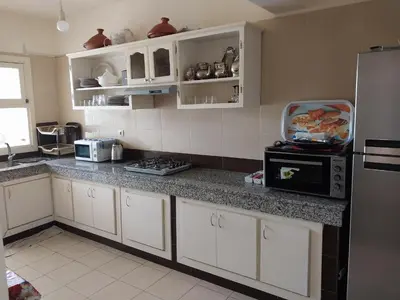 a kitchen with white cabinets and a black refrigerator at Appartement Hay Riad in Rabat
