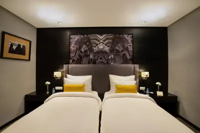 two beds with yellow pillows in a hotel room at ODYSSEE Boutique Hotel Casablanca in Casablanca