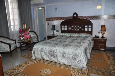 a bedroom with a bed and a table and chairs at Hôtel Transatlantique in Casablanca