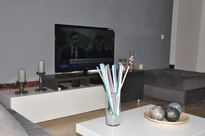a living room with a television and a vase with sticks at Elegant Apartment with Balcony in Val Fleuri, Maarif Casablanca, Perfect for Family & Corporate Stays in Casablanca