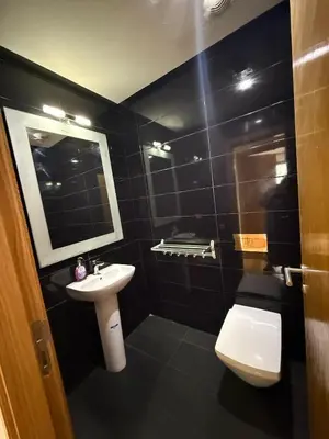 a black tiled bathroom with a toilet and a sink at Appartement Casa-marina au 10ème étage in Casablanca