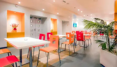 a restaurant with white tables and red chairs at Premiere Classe Casablanca Centre Ville in Casablanca