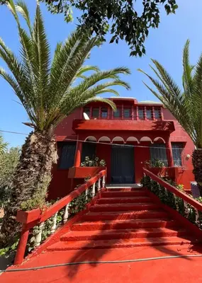a red building with stairs leading to a palm tree at villa waresa in Derroua