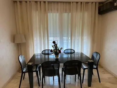 a dining room table with chairs and a vase with flowers at Appartement Casablanca vue sur mer in Casablanca