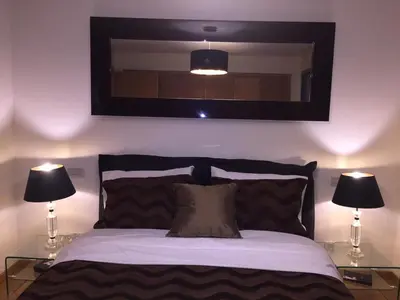 a bedroom with a bed with two lamps and a mirror at luxury apartment in Marina Casablanca in Casablanca