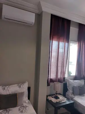 a room with two beds and a window and a table at Appartement avec terrasse au cœur du centre-ville de Rabat in Rabat