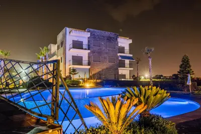 a villa with a swimming pool in front of a building at Garden Bay Appart'Hôtel in Casablanca
