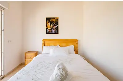a bedroom with a white bed with a wooden headboard at Gîte équestre Balade plage petit déjeuner au bord de la piscine in Azemmour