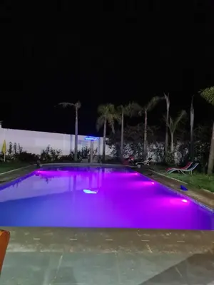 a swimming pool lit up purple at night at Gîte équestre Balade plage petit déjeuner au bord de la piscine in Azemmour