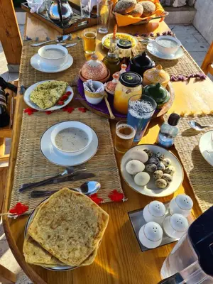 a wooden table with plates of food on it at Gîte équestre Balade plage petit déjeuner au bord de la piscine in Azemmour