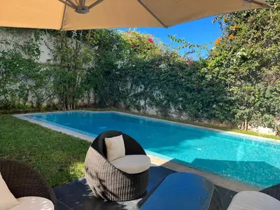 a swimming pool with a chair and an umbrella at Villa moderne avec piscine, front de mer in Casablanca