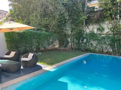 a swimming pool with a table and an umbrella at Villa moderne avec piscine, front de mer in Casablanca