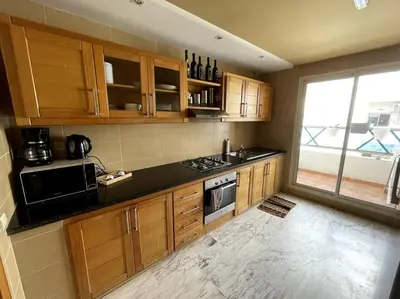a kitchen with wooden cabinets and a black counter top at Late&Early Flight cozy Apartment in Nouaseur