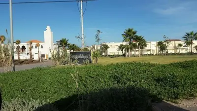 a field of grass with a building in the background at Dar Lazraq in Sidi Rahal