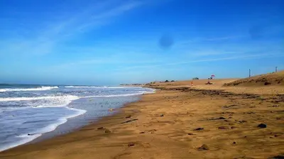 a beach with the ocean and people on the sand at Dar Lazraq in Sidi Rahal