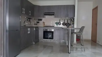 a kitchen with wooden cabinets and a table with a fireplace at Dar Lazraq in Sidi Rahal