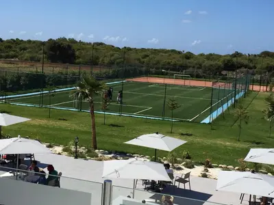 a tennis court with white umbrellas and a tennis court at Magnifique Villa a Savannah Beach in Sidi Rahal