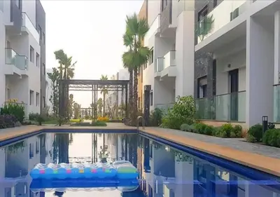 a swimming pool in front of a building at Charmant Appartement avec une vue imprenable in Tamaris