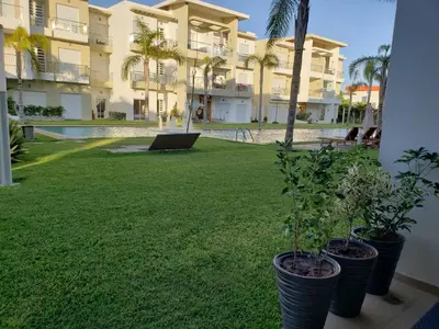 a yard with palm trees and a building at CASA BAY BEACH RETREAT in Sidi Rahal
