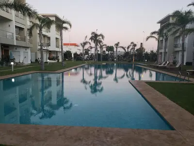 a large swimming pool with palm trees and buildings at CASA BAY BEACH RETREAT in Sidi Rahal