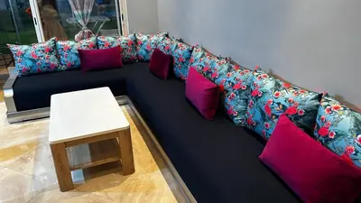 a blue couch with colorful pillows and a table at CASA BAY BEACH RETREAT in Sidi Rahal