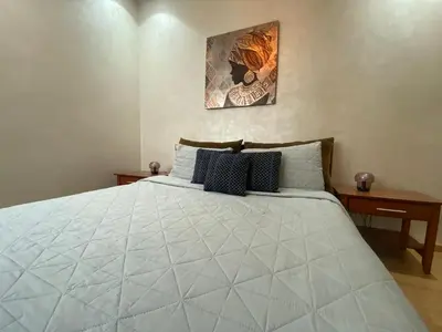 a bedroom with a large white bed with two tables at Appartement près de Novotel face au parc WELCOME STAY in Mohammedia