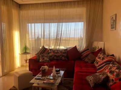 a living room with a red couch and a large window at Sea View Luxury Apartment Just Steps from the beach in Bouznika
