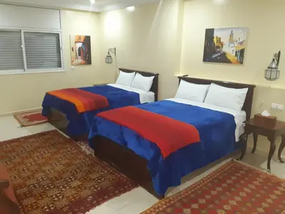 two beds in a room with blue and red sheets at Riad TANJIL in Casablanca