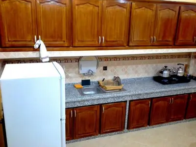 a kitchen with wooden cabinets and a white refrigerator at Silia Appartements in Temara