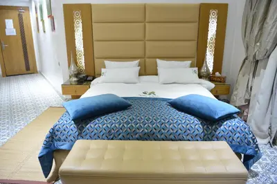 a bedroom with a large bed with blue pillows at Aralia Boutique Hôtel in Rabat