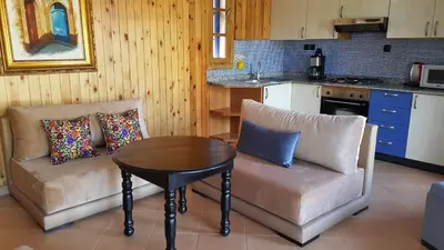 a living room with a table and a couch and a kitchen at Palmeraie skhirat1 in Skhirat