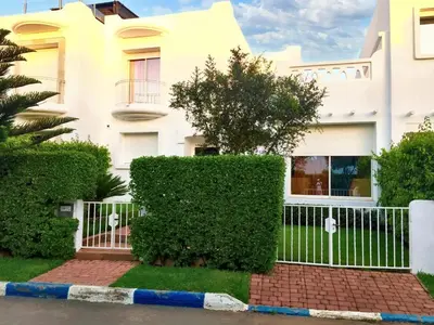 a white house with a fence and bushes at Elegant villa in Dar Bouazza with year-round private pool in Dar Bouazza