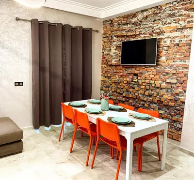 a dining room with a white table and orange chairs at Magnifique Appart a Savannah Beach in Sidi Rahal